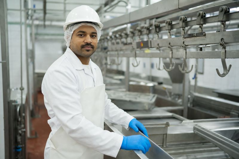 Worker in white hygiene uniform at a clean stainless-steel processing line